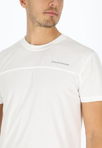 Hvid sports-T-shirt lavet af struktureret stof. Har en rund halsudskæring og en vandret stribe med "SWEDEMOUNT" logo. Korte ærmer.