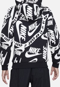 Huppari, jossa musta pohja, jossa toistuva valkoinen kuvio "Nike"-logoista ja sloganista. Elastiset hihansuut ja helma. Pehmeä kangas.