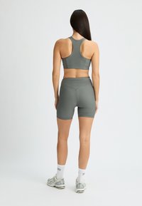 Reggiseno sportivo grigio e pantaloni corti abbinati con una texture a costine. Design a corsetto e pantaloni corti a vita media, abbinati a scarpe da ginnastica leggere e calze.