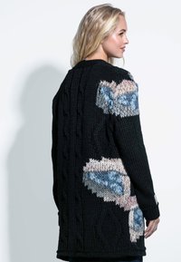 Czarny dzianinowy kardigan z fakturowanymi wzorami w warkocze oraz dużymi, kolorowymi haftami kwiatowymi w jasnoniebieskim i miękkim różowym na ramionach.