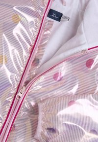 Transparent regnjacka med rosa dragkedja, rosa-randigt tyg och flerfärgade prickar som ligger platt, visar inredning i vit foder och märkesetikett.