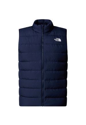 Chaleco acolchado azul marino con cuello alto, que presenta un cierre frontal y un diseño de acolchado horizontal. Logotipo visible en la parte superior izquierda.