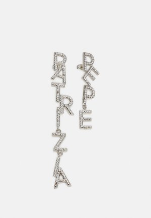 Srebrne kolczyki wiszące z literami ozdobionymi kryształkami, na jednym napis "PRATZLA", na drugim "REPE".