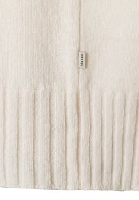 Hellcremer Strickpullover mit geripptem Saum, weicher Textur und kleinem Etikett mit dem eingewebten Schriftzug "Maerz" an der Seite.