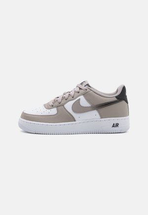 Niskie buty Nike Air Force 1 w kolorze białym i beżowym z szarym znakiem Swoosh, białą podeszwą i napisem „AIR” na boku śródpodeszwy.