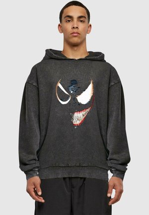 Dark gray hoodie features a large graphic of a stylized, menacing face with sharp teeth and exaggerated eyes in black and white with red accents.