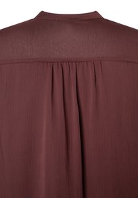 Bordeauxfarbige Bluse mit plissiertem Rücken, weichem Material und dezenter Struktur. Sie hat einen schlichten Ausschnitt und eine lässige Silhouette ohne Verzierungen.