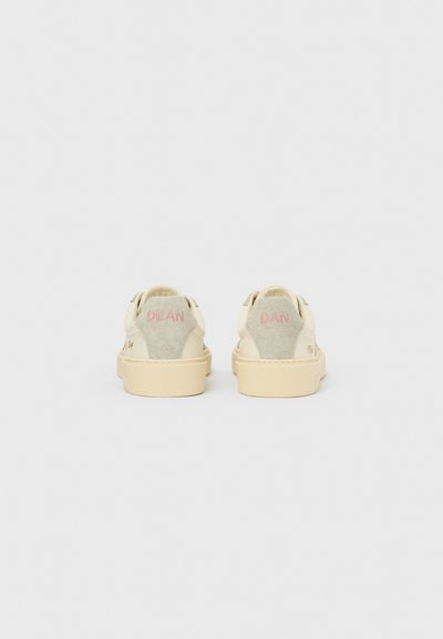 Pantofi sport de culoare crem cu accente din piele întoarsă, având o talpă bej, detalii cusute și inscripțiile „DEAN” și „DAN” brodate pe spate.