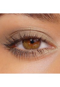 Primo piano di un occhio marrone con ombretto dorato scintillante, ciglia ben definite e una texture della pelle liscia attorno alla palpebra.