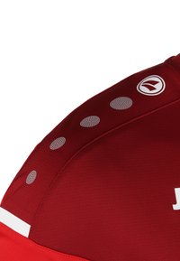 Rotes Sportshirt aus glattem Gewebe. Verfügt über reflektierende, gepunktete Akzente und ein weißes Logo auf der Schulter.