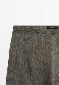 Jupe en lin gris foncé avec une ceinture pliée, des coutures visibles et une étiquette indiquant Massimo Dutti fabriqué au Maroc.