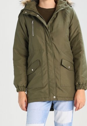 Olijfgroene parka met een bontgevoerde capuchon, rits- en drukknoopsluitingen, elastische manchetten en twee voorzakken. Heeft een gladde, waterdichte stof.