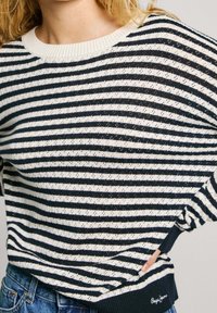 Marinblå och vit randig stickad tröja med en ribbad rund hals och nederkant, som har texturerad tyg och sidoöppningar för extra detalj.