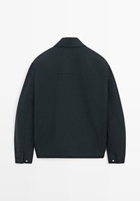 Giacca blu navy scuro con colletto vista da dietro, con maniche lunghe e polsini con bottoni su uno sfondo semplice.