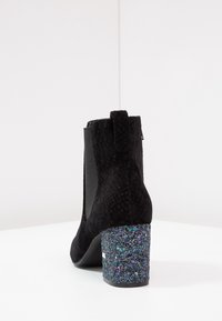 Bottines noires avec une tige texturée, des panneaux latéraux élastiques et un talon chunky pailleté. Comprend une languette pour un enfilage facile.