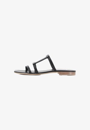 Sandalia deslizante de cuero negro con dos correas superiores, suela plana y un acento de madera de color claro en el tacón. Textura suave, diseño minimalista.