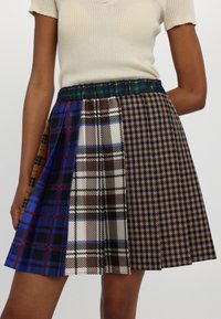 Falda plisada multicolor con varios patrones de cuadros en azul, marrón y verde. Cintura elástica y tela ligera.