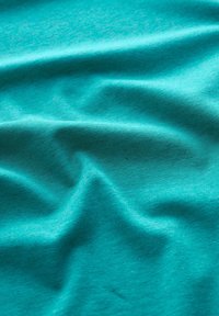 Teal tyg som visar en mjuk, slät textur med lätta vecken och ett subtilt melerat mönster genom hela. Lätt och något stretchig.