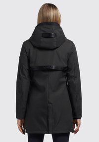 Veste imperméable noire avec capuche, dotée d'une taille cintrée, de manches longues et d'une bande de logo réfléchissante à l'arrière.