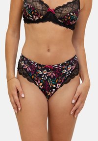 Culotte en dentelle noire et en tissu avec un motif floral dans les tons de rose, vert et orange. Dotée de bords festonnés et d'un petit nœud rose en accent.