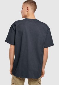 Mørkegrå oversized t-skjorte med rund hals, korte ermer og strukturert stoff. En grunnleggende design uten synlige mønstre eller aksenter.