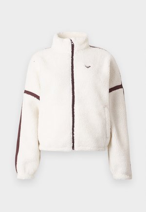 Chaqueta de forro polar blanca con cremallera frontal completa, cuello alto y rayas marrones a lo largo de las mangas y la línea de la cremallera.