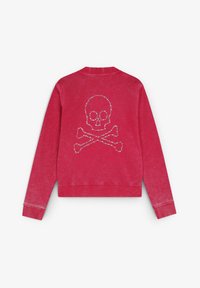 Felpa rosa con scollo rotondo, caratterizzata da un design di teschio e ossa incrociate in strass sul retro. Il tessuto ha una consistenza sbiadita.