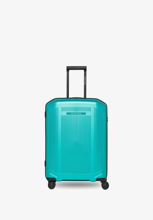 Turkooizen harde koffer met verticale ribbels, vier zwenkwielen en uitgeschoven zwarte telescopische handgreep.