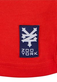 Rød bomulds skjorte med et blåt patch og et hvidt grafisk logo samt teksten "ZOO YORK." Glat tekstur med en rund kant.