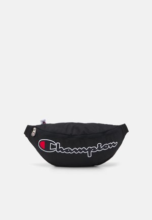 Riñonera de tela negra con el logo de Champion en blanco y rojo, cierre de cremallera y correa ajustable sobre un fondo liso.