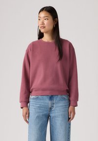 Μπλουζάκι ματζέντα με στρογγυλή λαιμόκοψη, κατασκευασμένο από απαλό ύφασμα με ριμπ μανσέτες και τελείωμα. Συνδυάζεται με ανοιχτόχρωμα μπλε τζιν για άνετη εφαρμογή.