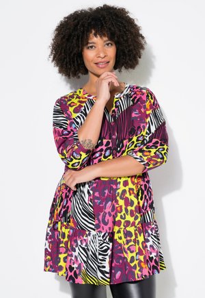 Túnica colorida con una mezcla de estampados de animales, incluyendo patrones de cebra y leopardo, con mangas de tres cuartos y un dobladillo en capas.
