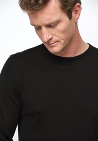 Schwarzer, langärmeliger Strickpullover mit runder Halsausschnitt, gerippten Bündchen und glatter Textur, teilweise sichtbar an einem Modell.