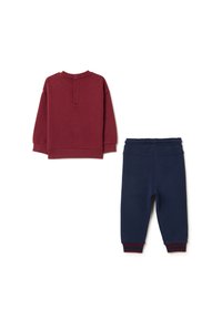 Rotes Sweatshirt mit rundem Ausschnitt und Knopfverschluss, kombiniert mit navyfarbenen Jogginghosen mit elastischem Bund und roten gestreiften Bündchen.