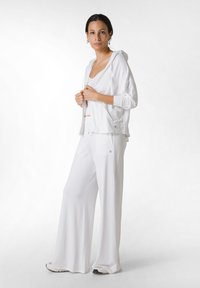 Valkoinen kevyt huppari rentoa istuvuutta varten, yhdistettynä yhteensopiviin löysiin housuihin. Sileä pinta ja minimalistinen muotoilu, sopii arkipukeutumiseen.