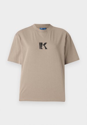 Camiseta beige de manga corta hecha de algodón con cuello redondo y un diseño gráfico en negro que presenta una letra "K" y una silueta.