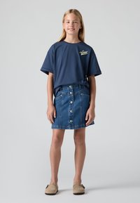 Tamnoplava pamučna majica s kratkim rukavima i "Levi's" logotipom na prsima, u kombinaciji s plavom traper suknjom s gumbima sprijeda. Mekani materijal, ležeran kroj.