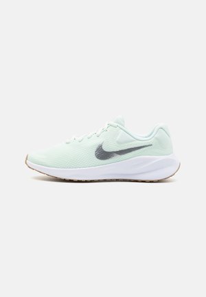 Lysegrøn Nike løbesko med hvid sål og sort Nike swoosh, vist fra ydersiden på en hvid baggrund.