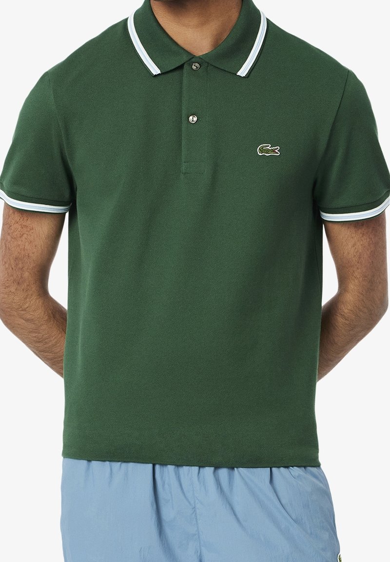 Zielona koszulka polo z teksturowanej tkaniny, z dwoma guzikami, kołnierzykiem i mankietami w białe i niebieskie paski oraz detalem logo.