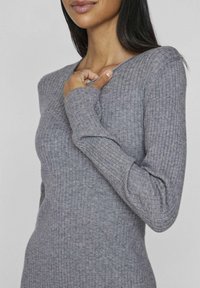Gray ribbed long-sleeve knit top with a round neckline. Features a fitted silhouette and textured fabric for added interest.