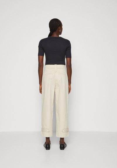 Marineblauw T-shirt met korte mouwen en een getailleerde pasvorm, gecombineerd met beige wijde broekspijpen met omslagen en achterzakken.