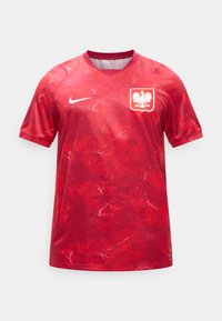 Maillot de football Nike rouge avec motif d'éclairs blancs, swoosh blanc sur la poitrine droite, et emblème de l'aigle de l'équipe nationale de Pologne sur la poitrine gauche.