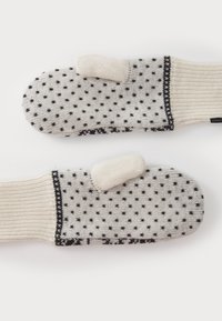 Gestrickte Fäustlinge in Creme und Schwarz mit Punkten; verfügen über eine Daumenöffnung und ein geripptes Bündchen für einen sicheren Sitz. Weiche Textur und warmes Design.