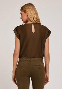 Short-sleeve brown blouse with a keyhole back detail, paired with matching high-waisted olive green pants. Soft fabric, relaxed fit.