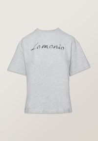 Sivý tričko s krátkym rukávom a voľným strihom, na chrbte so zašitým ručne písaným logom "Lomania" čiernou niťou.