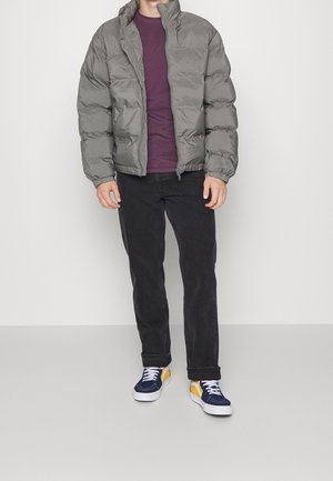 Puffy grey jacket with high collar, a maroon shirt underneath, black jeans, and blue sneakers with yellow accents.