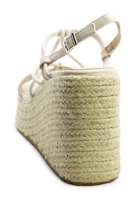 Beige espadrille wedge sandaal met een gevlochten jute zool, voorzien van een gekruist bandontwerp en verstelbare enkelgesp.