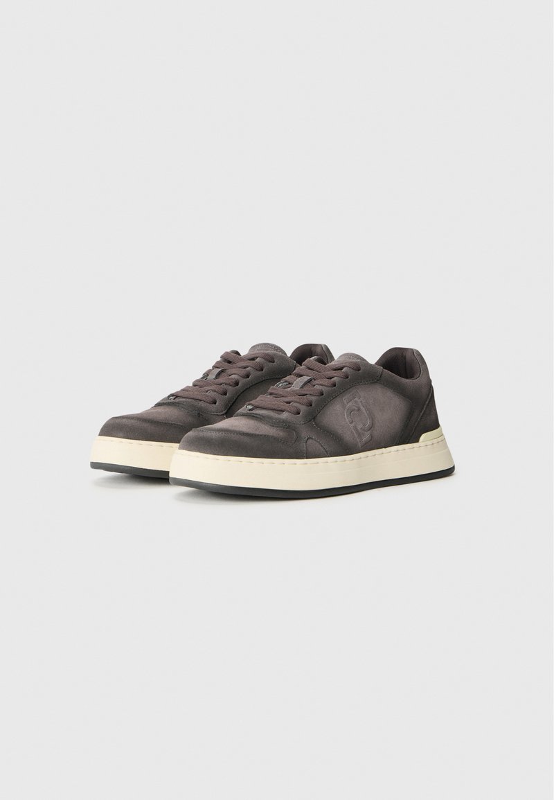 Donkergrijze suède sneakers met een ronde neus, beige rubberen zool en bijpassende veters. Voorzien van een logo-detail aan de zijkant en gestikte accenten.