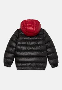 Čierna puffer bunda s horizontálnym prešívaním a jasne červenou vycpanou kapucňou, elastickými manžetami a spodným lemom, zobrazená zozadu na bielom pozadí.