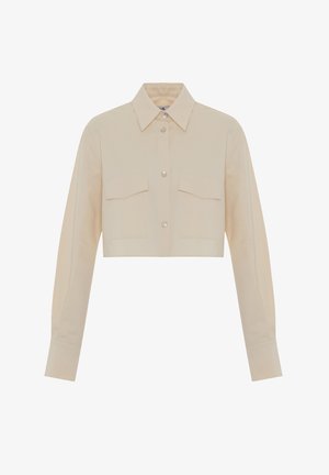 Bovenstuk met korte mouwen in crèmekleurige stof, met lange mouwen, twee borstzakken en parelknoopjes. Glad textuur met een klassieke kraag.